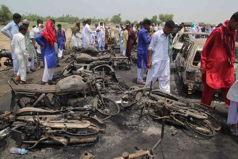 Pakistani villagers gathering at the site of a deadly oil tanker fire followin